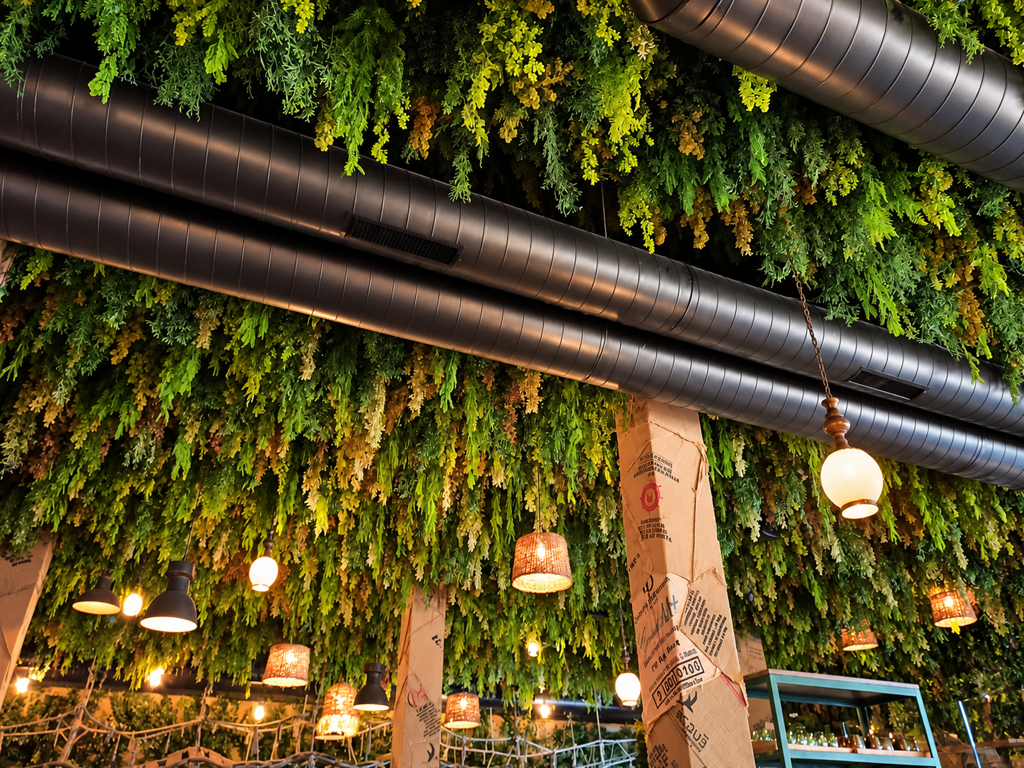 Conductos metálicos de climatización integrados en un local con vegetación decorativa